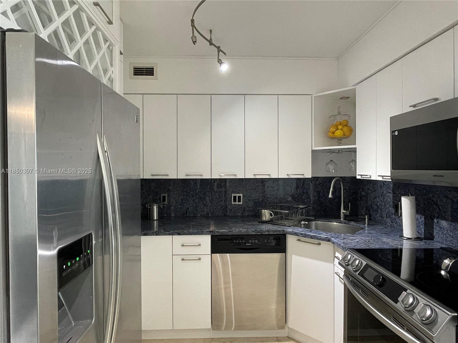 5151 Collins Avenue, Unit 825 Miami Beach, FL 33140 - Photo 10 of 28 a kitchen with stainless steel appliances granite countertop a stove a refrigerator and a sink