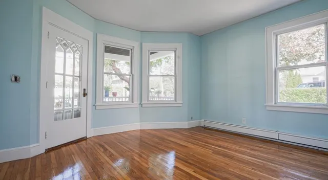 a view of empty room with wooden floor and fan