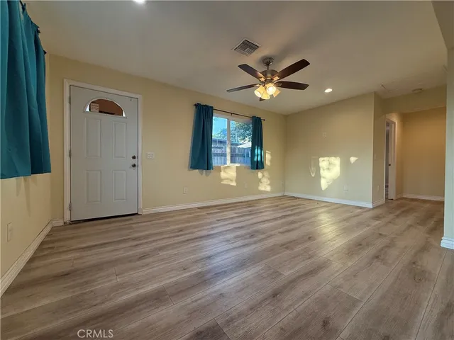 a view of an empty room with window and wooden floor