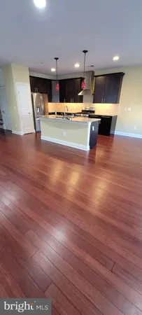 a view of a kitchen with kitchen island a stove a wooden floor and a large window