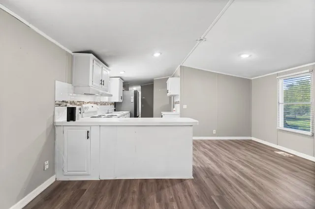 a large white kitchen with wooden floors and white walls