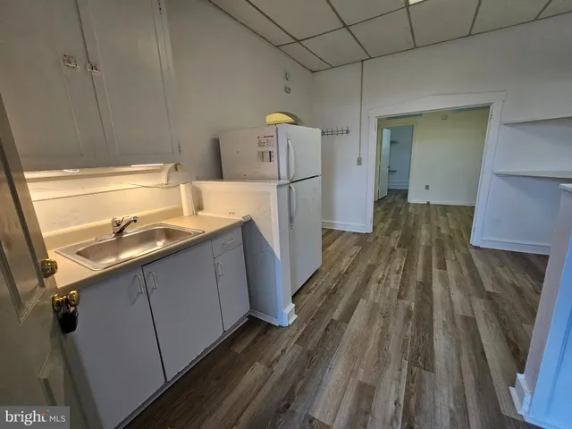a kitchen with a sink refrigerator and wooden floor