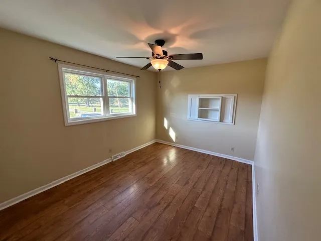 a view of an empty room with window and wooden floor