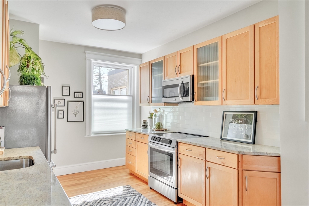 20 John Street, Unit 3 Brookline, MA 02446 - Photo 7 of 23 a kitchen with stainless steel appliances granite countertop a sink and a granite counter tops with a large window