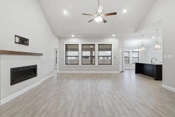 a view of an empty room with a fireplace and wooden floor