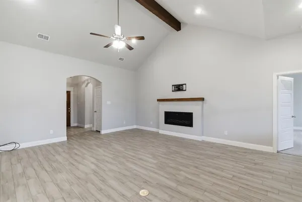 a view of an empty room with wooden floor and a fireplace