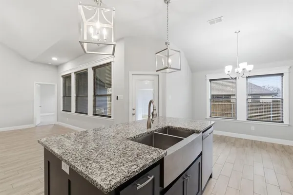 a kitchen with granite countertop a sink center island with wooden floor