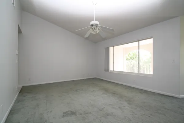 an empty room with a chandelier fan and windows