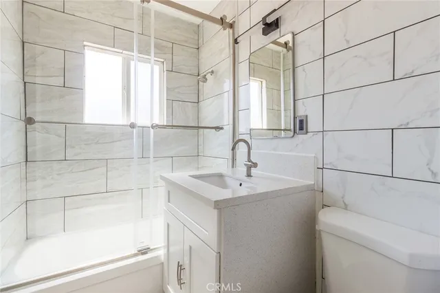 a bathroom with a sink and mirror with bathtub