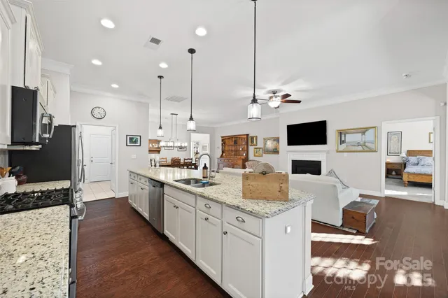 a large kitchen with kitchen island granite countertop a stove oven and a flat screen tv