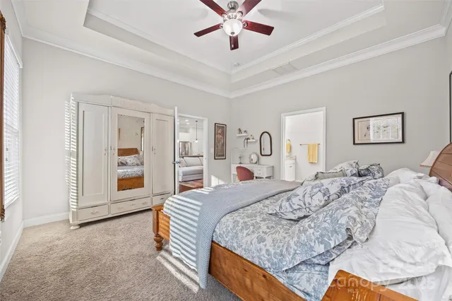a spacious bedroom with a bed a dresser and a chandelier
