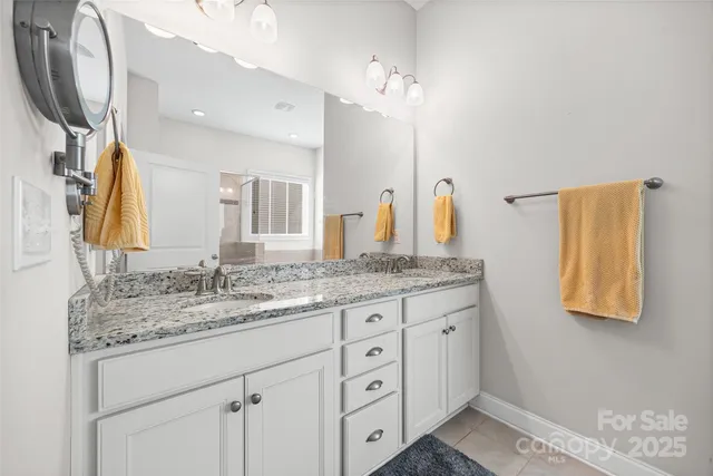 a bathroom with a granite countertop double vanity sink and a mirror