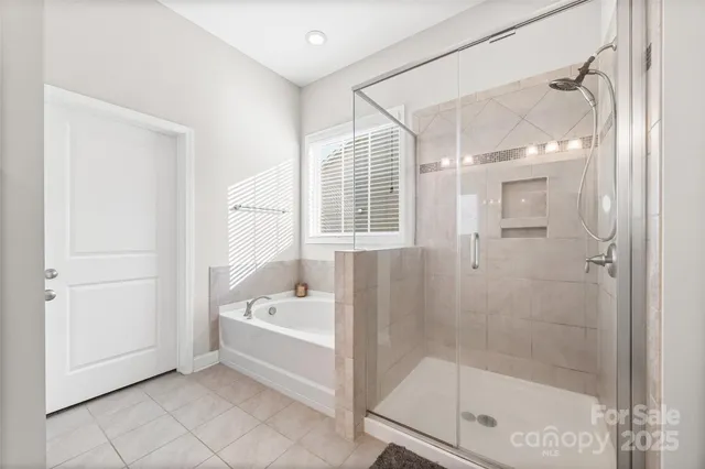 a bathroom with a tub a mirror and a shower