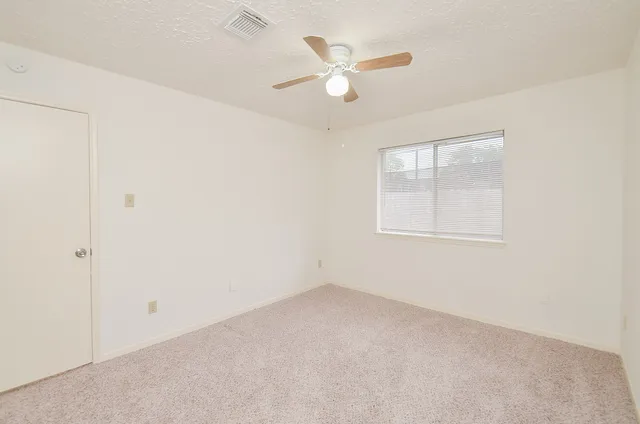 an empty room with a window and a fan
