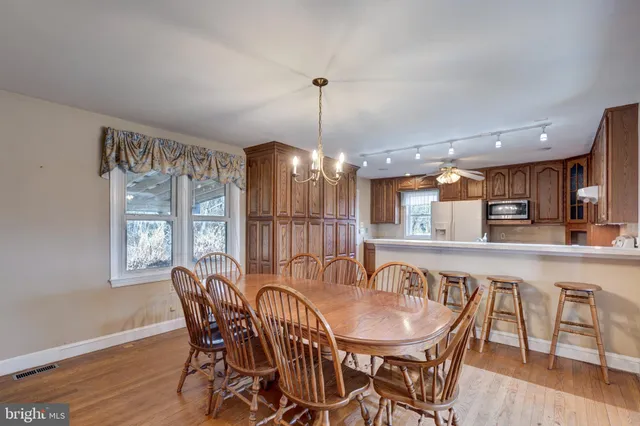 a kitchen with stainless steel appliances granite countertop a table chairs sink and cabinets