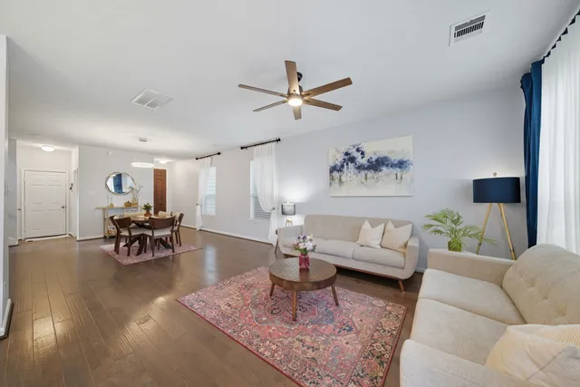 a living room with furniture and a dining table with wooden floor
