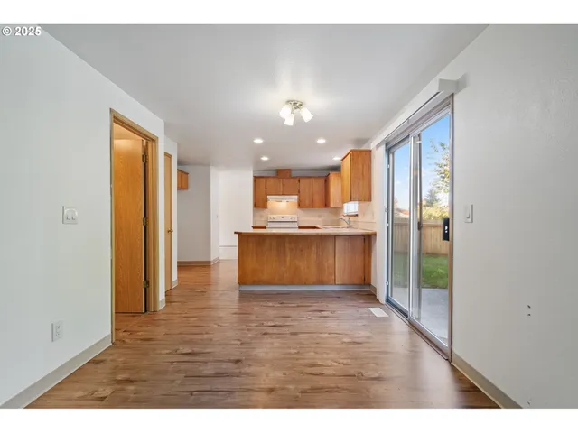 a view of kitchen with kitchen island granite countertop refrigerator cabinets and wooden floor