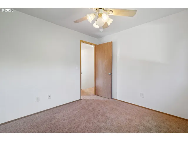 a view of an empty room and chandelier fan