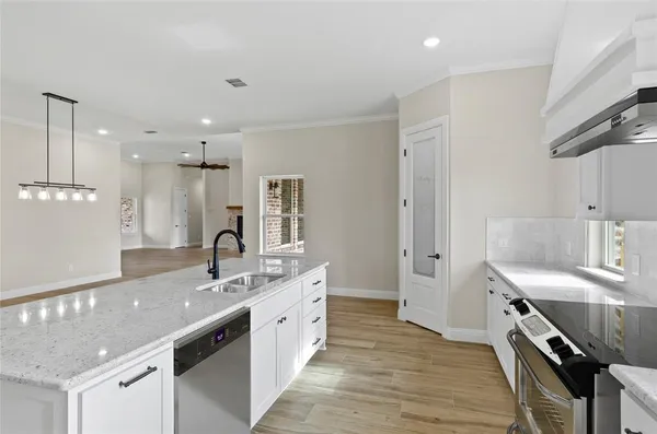 a view of a kitchen with kitchen island a sink wooden floor and a large window