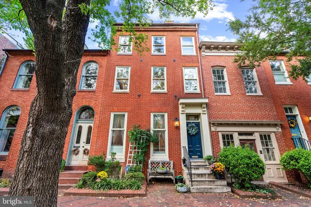 front view of a brick house with a large tree