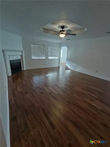 a view of a livingroom with wooden floor a ceiling fan and a window