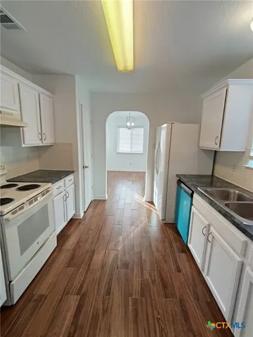 a kitchen with granite countertop wooden floors a stove and a sink
