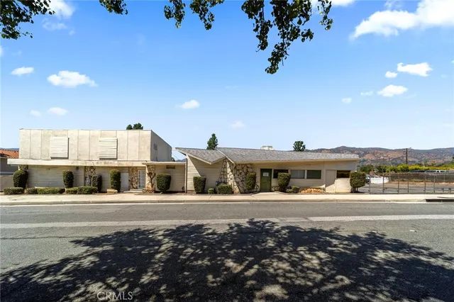 a front view of a building with a garden and plants