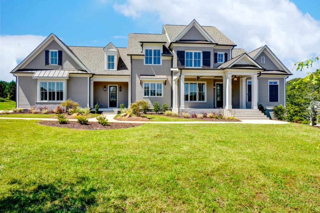 a front view of a house with garden and trees