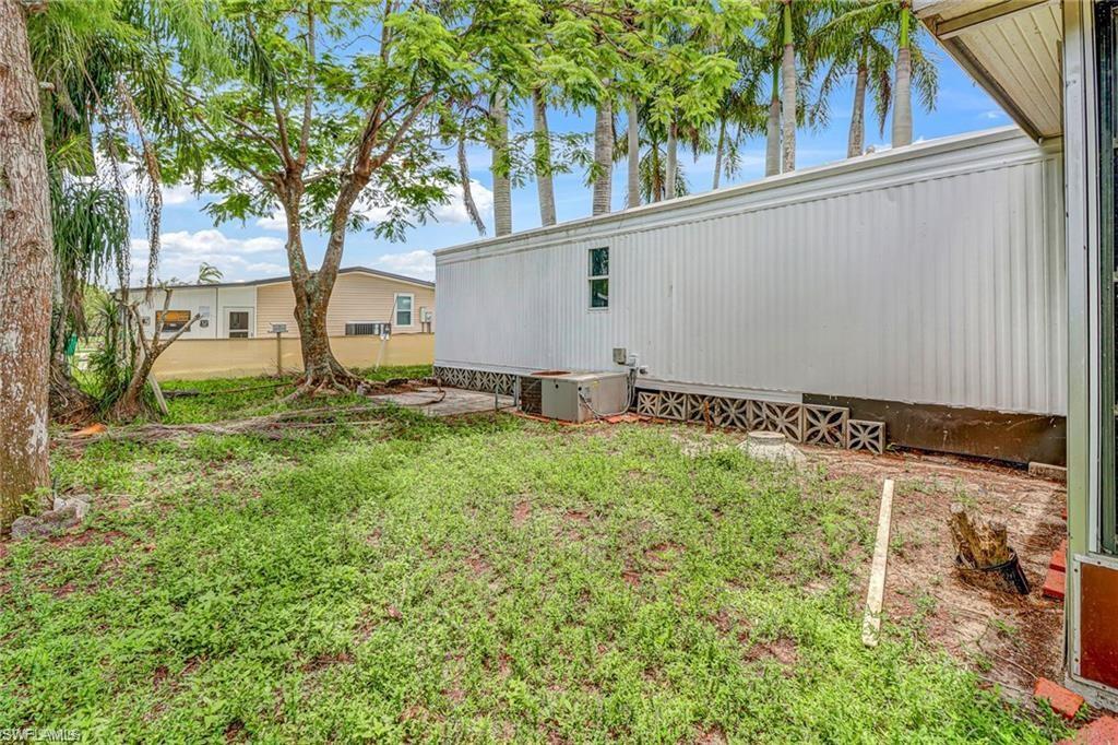120 Grassy Key Lane, Unit 38 Naples, FL 34114 - Photo 18 of 28 a backyard of a house with lawn chairs and a large tree