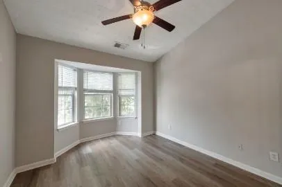 an empty room with chandelier fan and windows