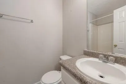 a bathroom with a granite countertop toilet sink and mirror