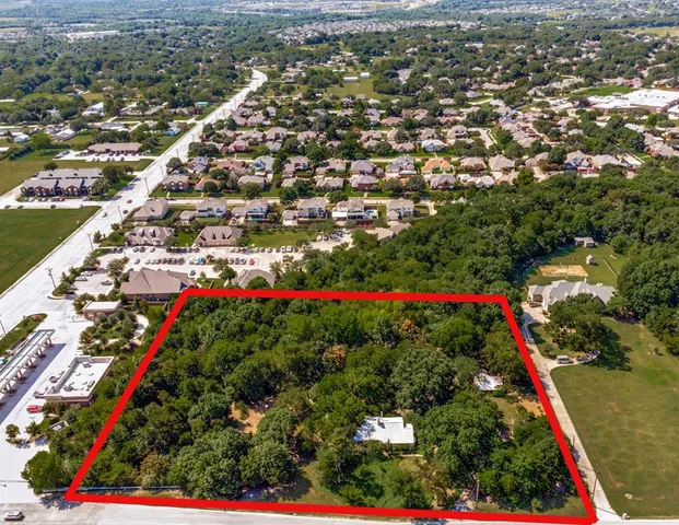 an aerial view of residential houses with outdoor space and trees