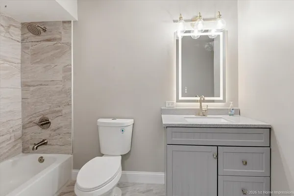 a bathroom with a toilet a sink a bath tub and mirror