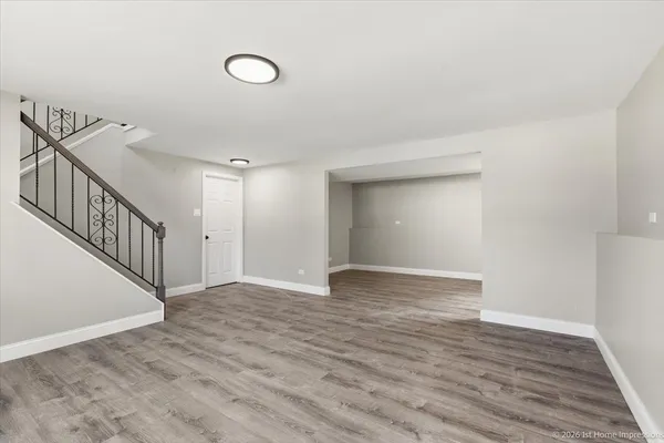 a view of an empty room with wooden floor and stairs