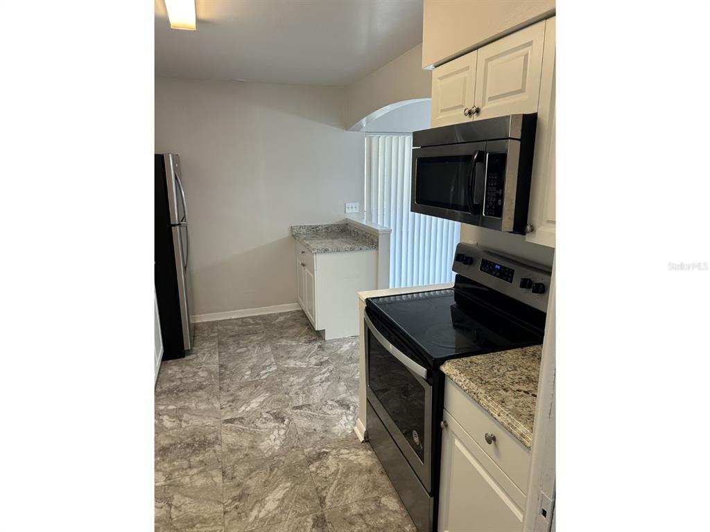 1241 Pilgrim Road Spring Hill, FL 34606 - Photo 8 of 28 a kitchen with stainless steel appliances granite countertop a stove and a refrigerator
