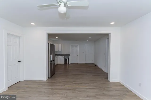 an empty room with wooden floor and a ceiling fan