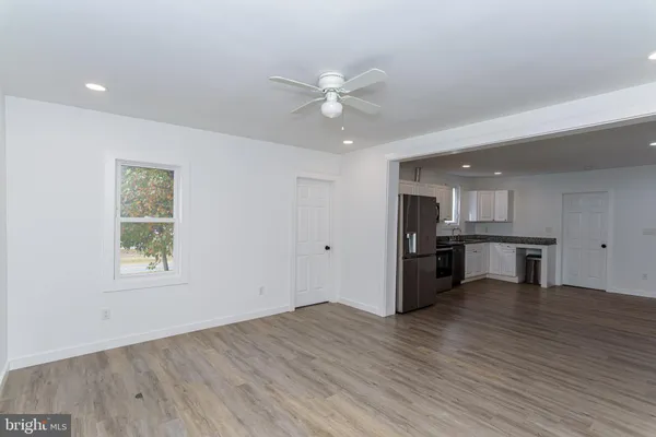 an empty room with wooden floor and fan