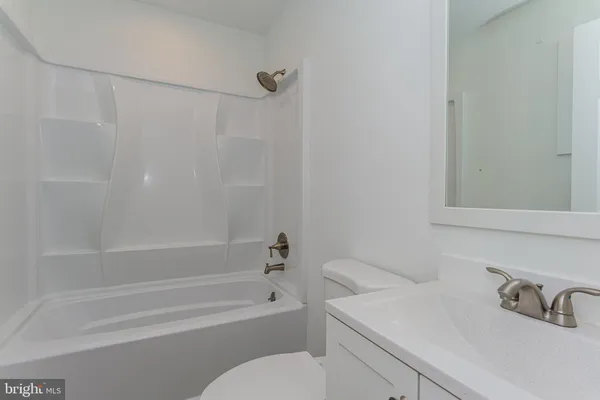 an empty room with wooden floor ceiling fan and windows