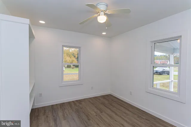 an empty room with wooden floor and fan