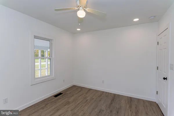 an empty room with wooden floor fan and windows