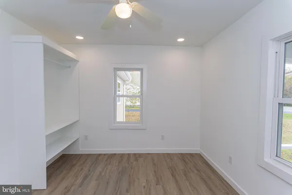 an empty room with wooden floor and ceiling fan