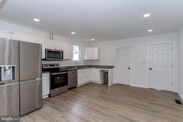 a kitchen with stainless steel appliances granite countertop a stove top oven a sink and a refrigerator