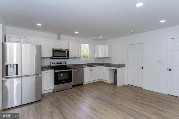a kitchen with granite countertop white cabinets and stainless steel appliances
