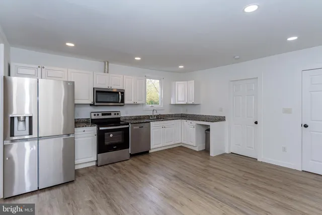 a kitchen with granite countertop white cabinets and stainless steel appliances