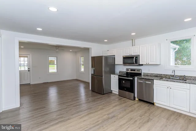 a view of a kitchen with wooden floor and a refrigerator