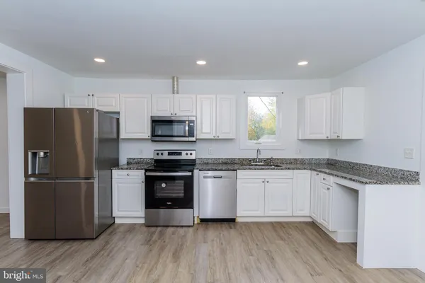 a kitchen with stainless steel appliances granite countertop a refrigerator and a stove top oven