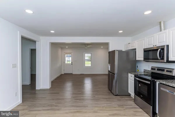 an empty room with wooden floor a ceiling fan and windows