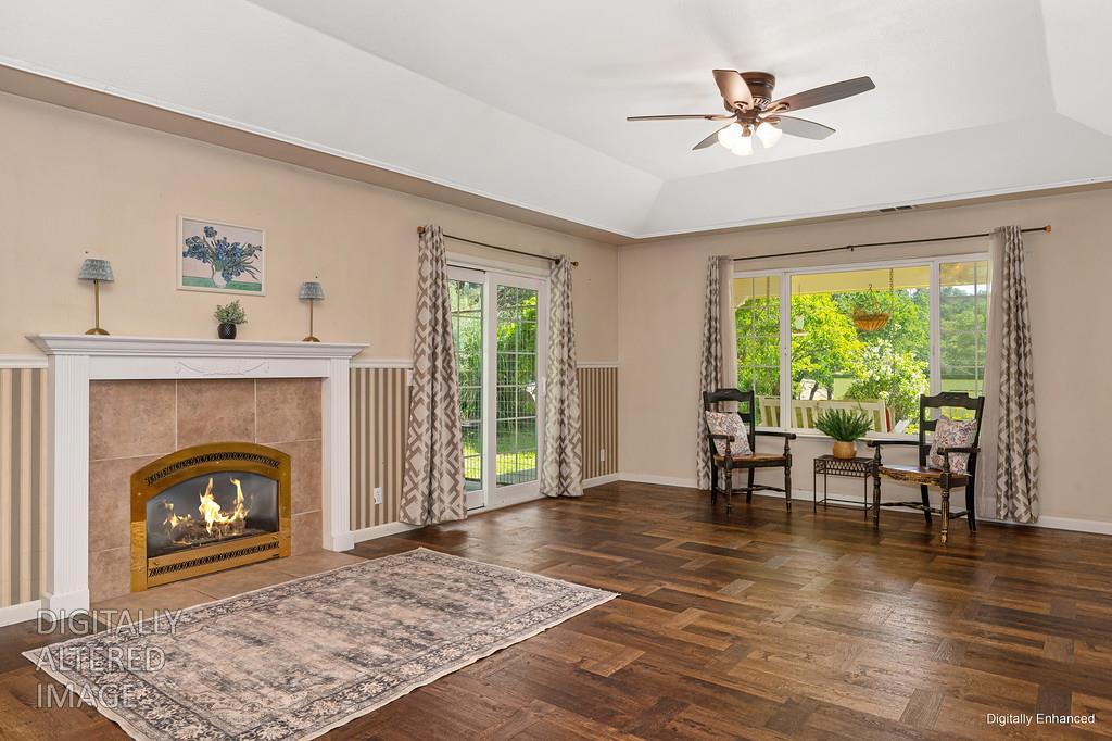 6181 Lambert Lane El Dorado, CA 95623 - Photo 21 of 68 living area with ceiling fan, dark wood finished floors, a raised ceiling, and a tile fireplace