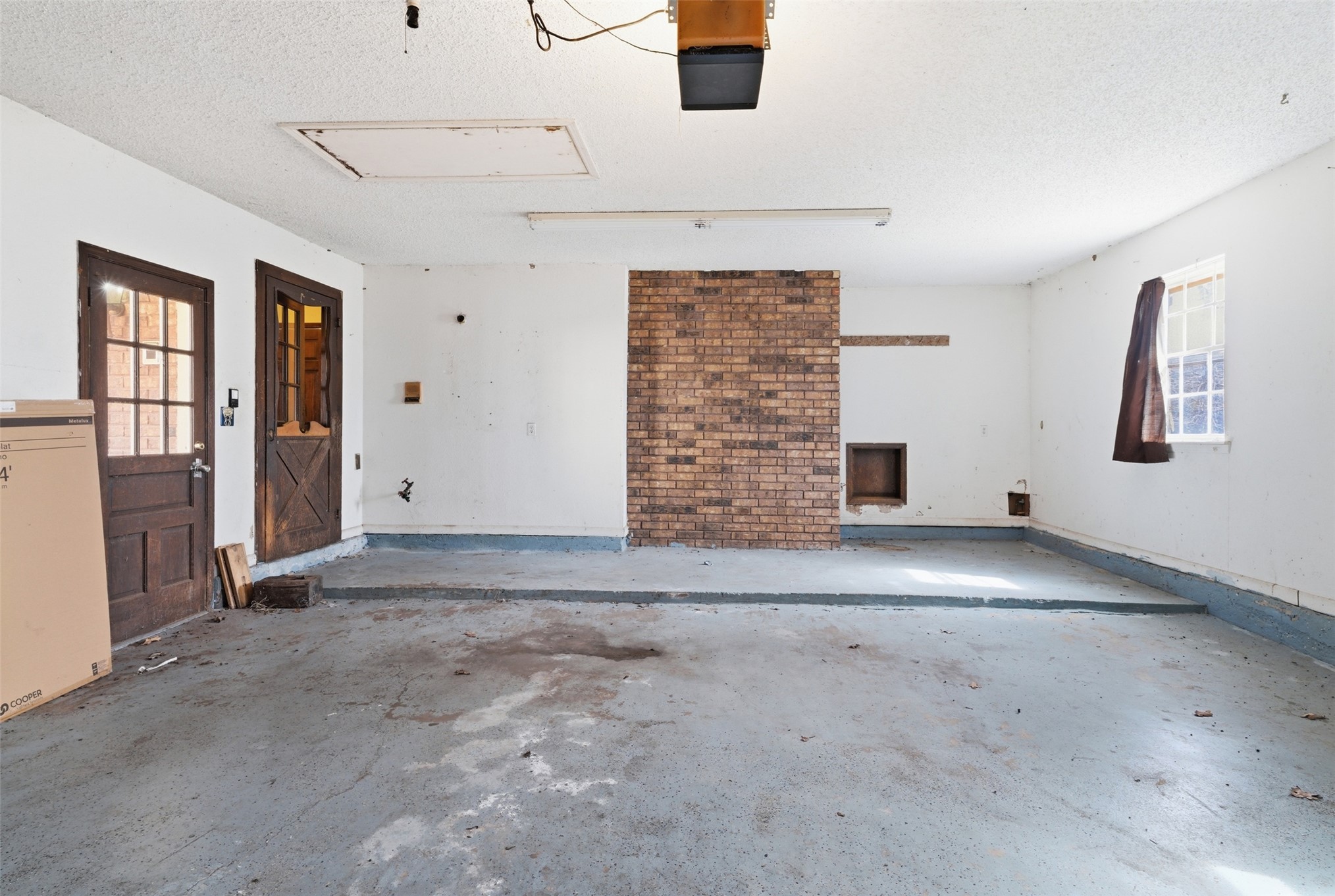 17875 East 589 Road Inola, OK 74036 - Photo 67 of 73 Concrete floor garage with multiple entry doors and a brick accent wall. Access door to fireplace to bring in firewood.