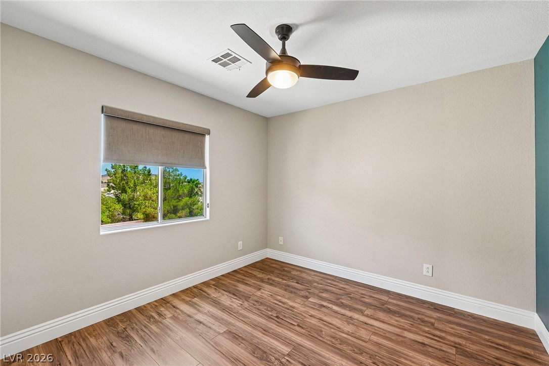 1176 Butternut Ranch Court Henderson, NV 89052 - Photo 20 of 60 A quiet bedroom retreat features a well-lit window overlooking vibrant greenery and elegant wood flooring.